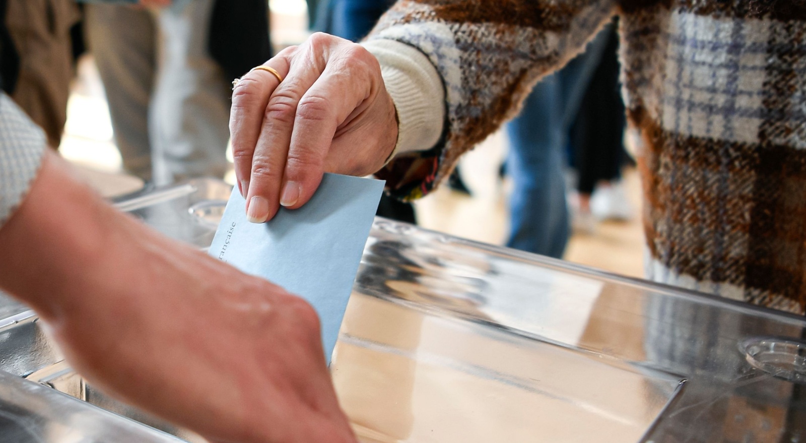 A person putting a ballot paper into a box.