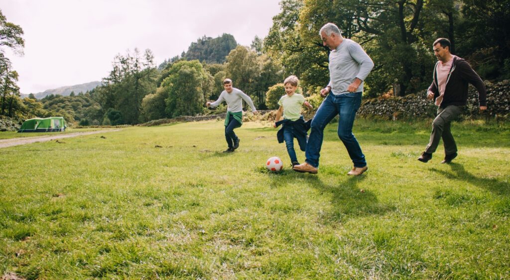 Multi-generational family playing football in a park.