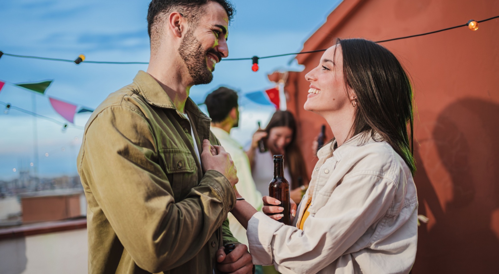 A young couple outside smiling at each other.