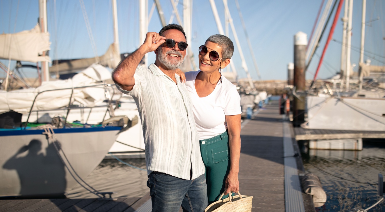 A couple posing on a marina pier.