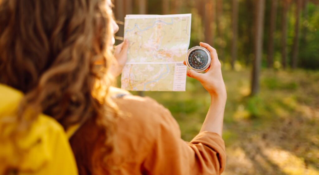 A young woman hiking and using a compass.