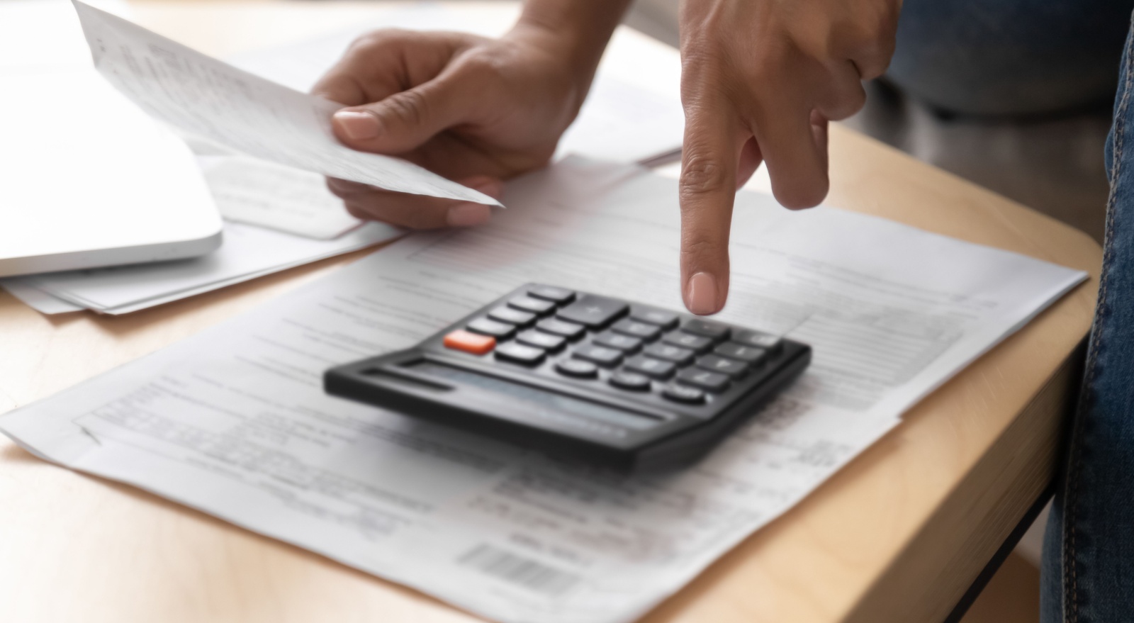 A person going through paperwork with a calculator.