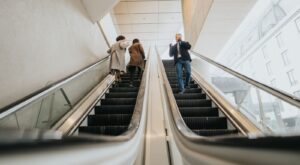 People using escalators in an office building.