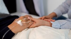 A patient holding hands with a loved one.