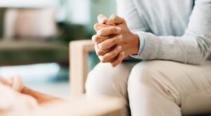 A woman sitting with her hands clasped.
