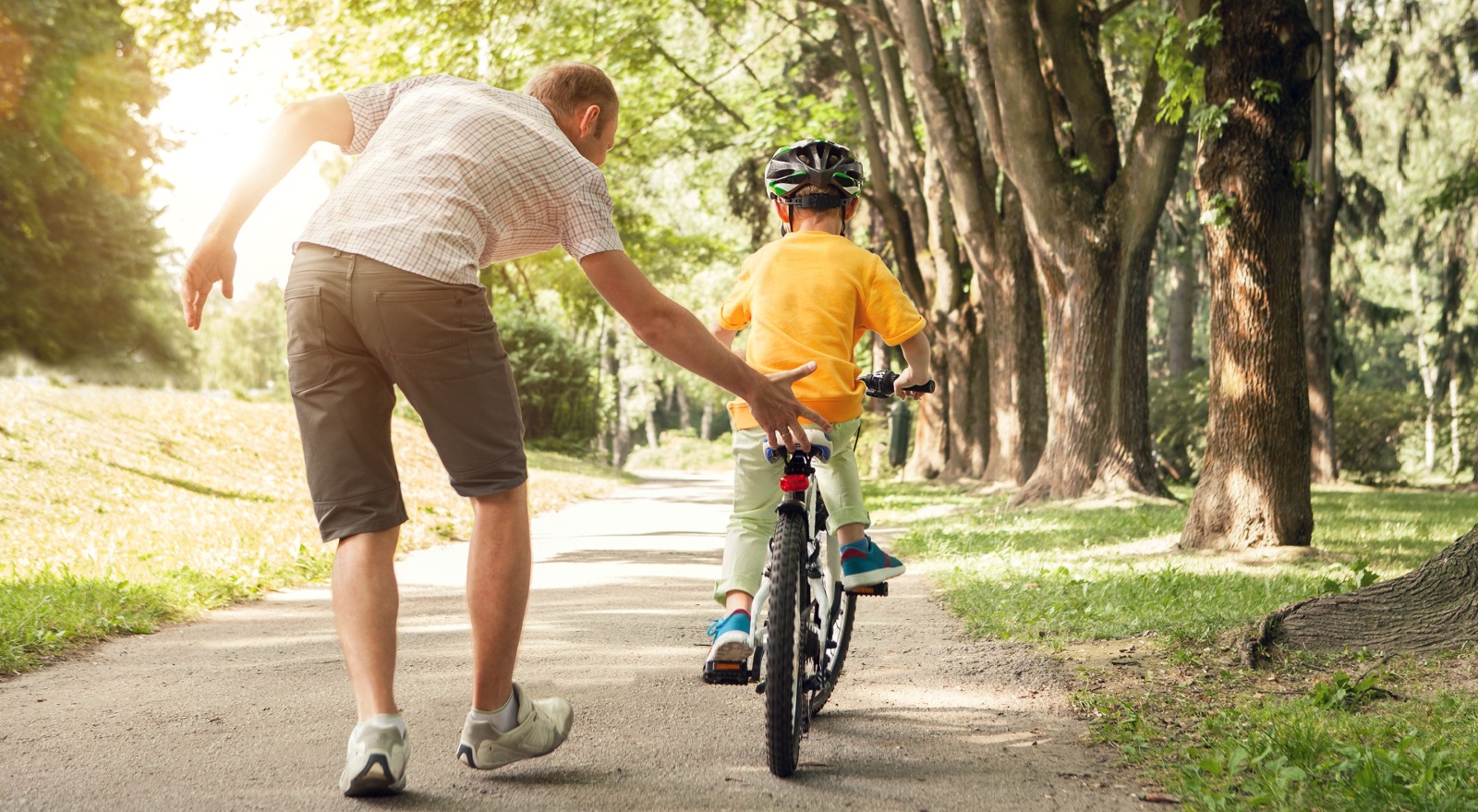 A father teaching a child to ride a bike.