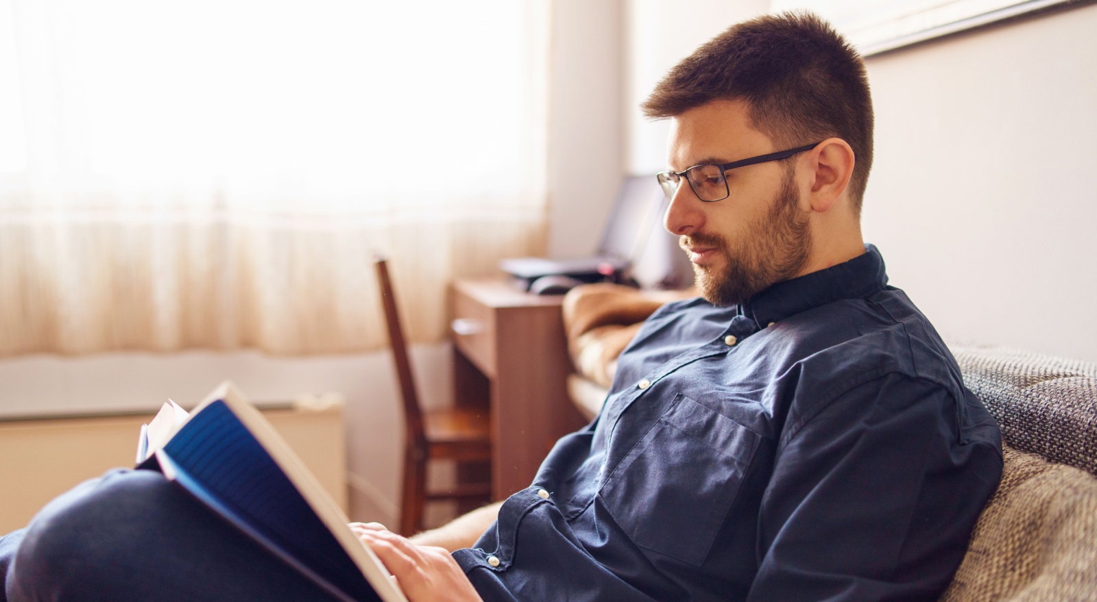 A man reading a book in his home.
