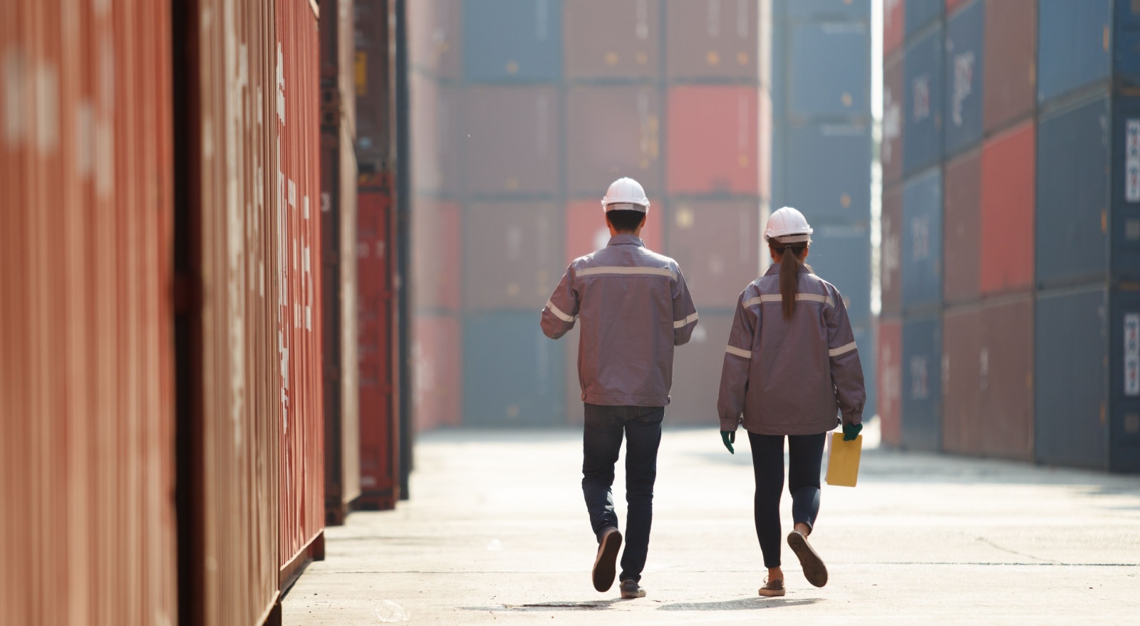 Two workers walking between shopping containers.