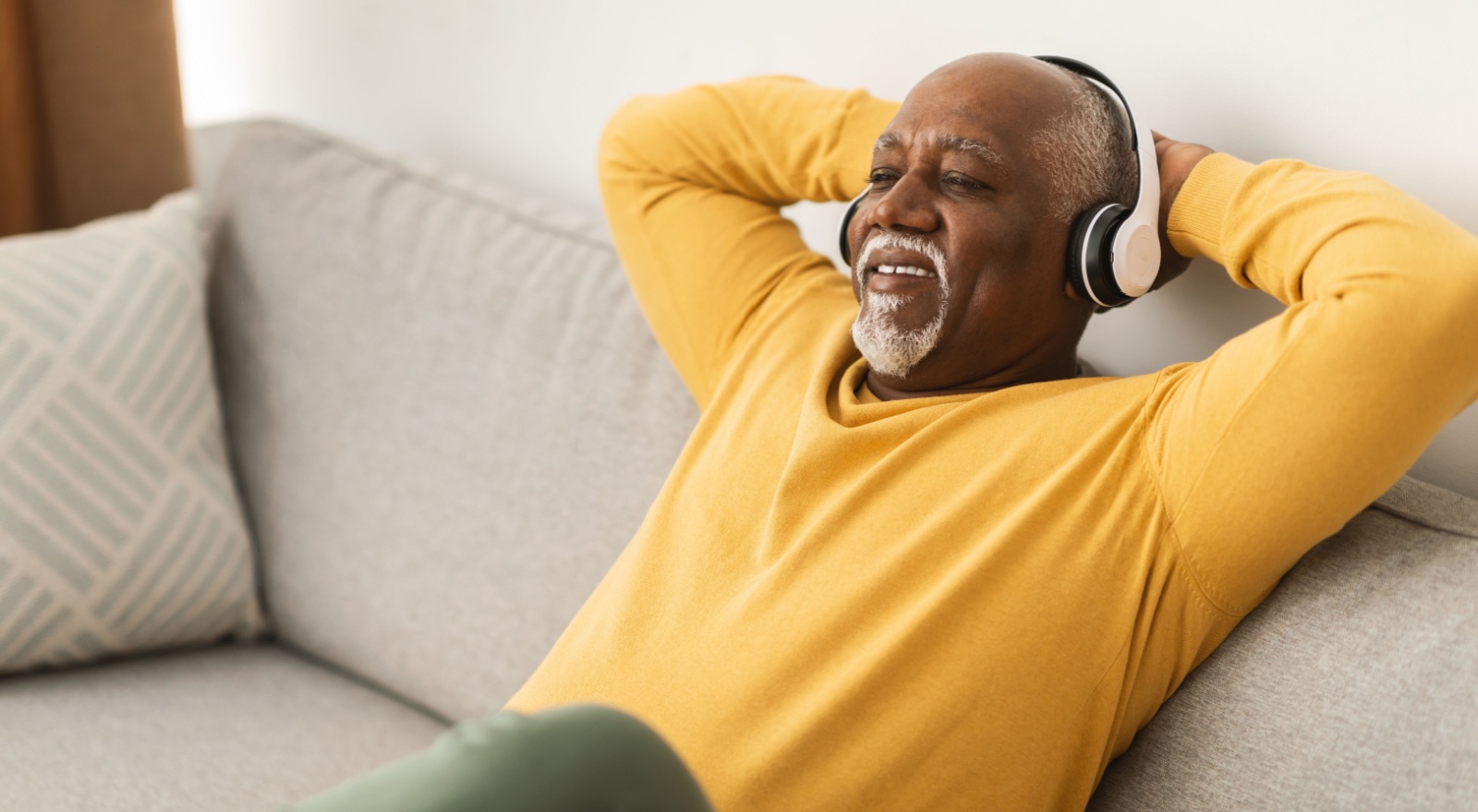 A man relaxing on a sofa with his hands behind his head.