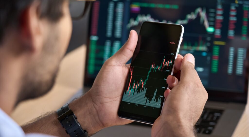 A man looking at a graph showing stock market performance on his phone.