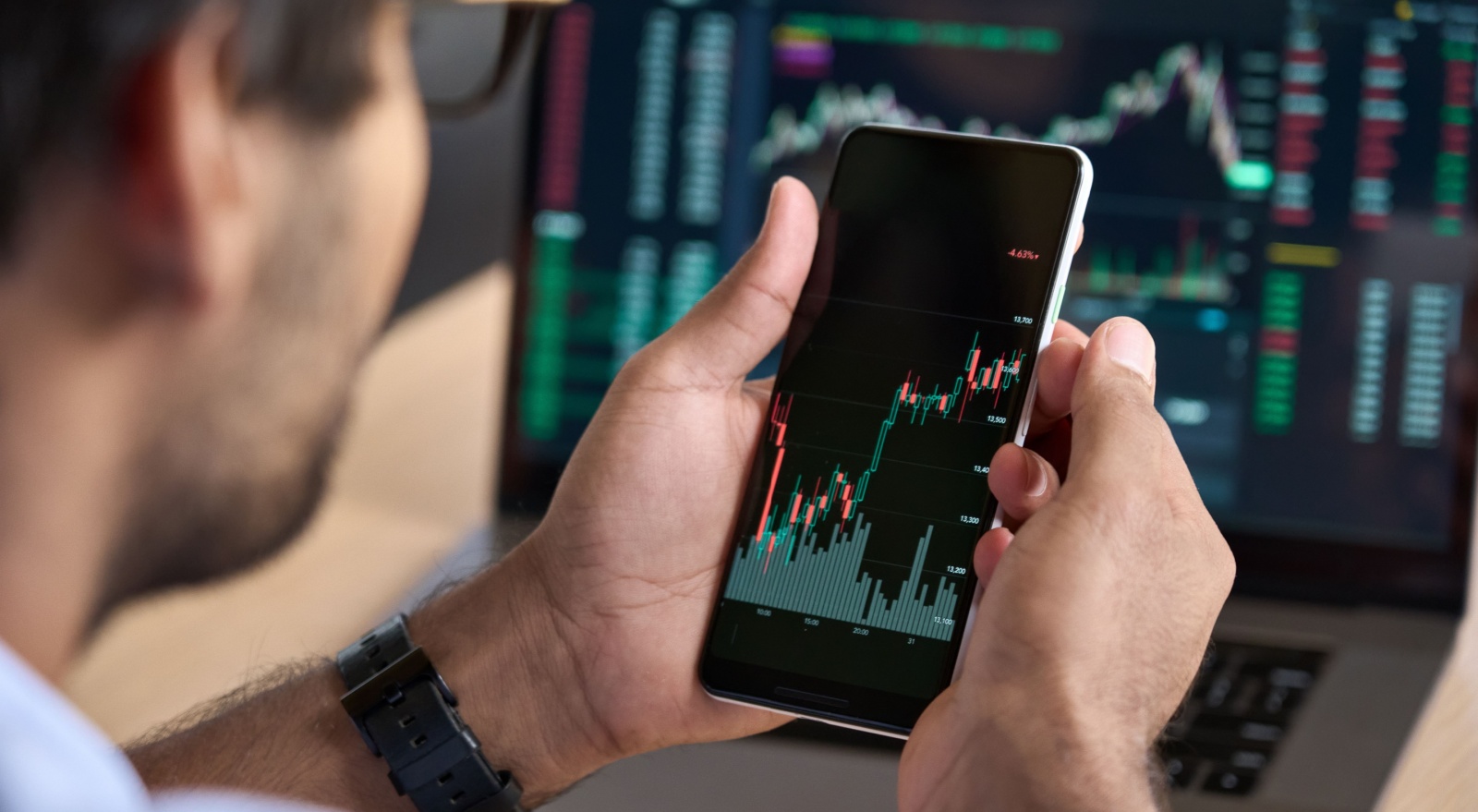 A man looking at a graph showing stock market performance on his phone.