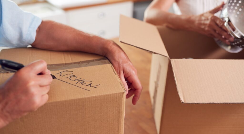 A close-up of a couple packing boxes to move home.