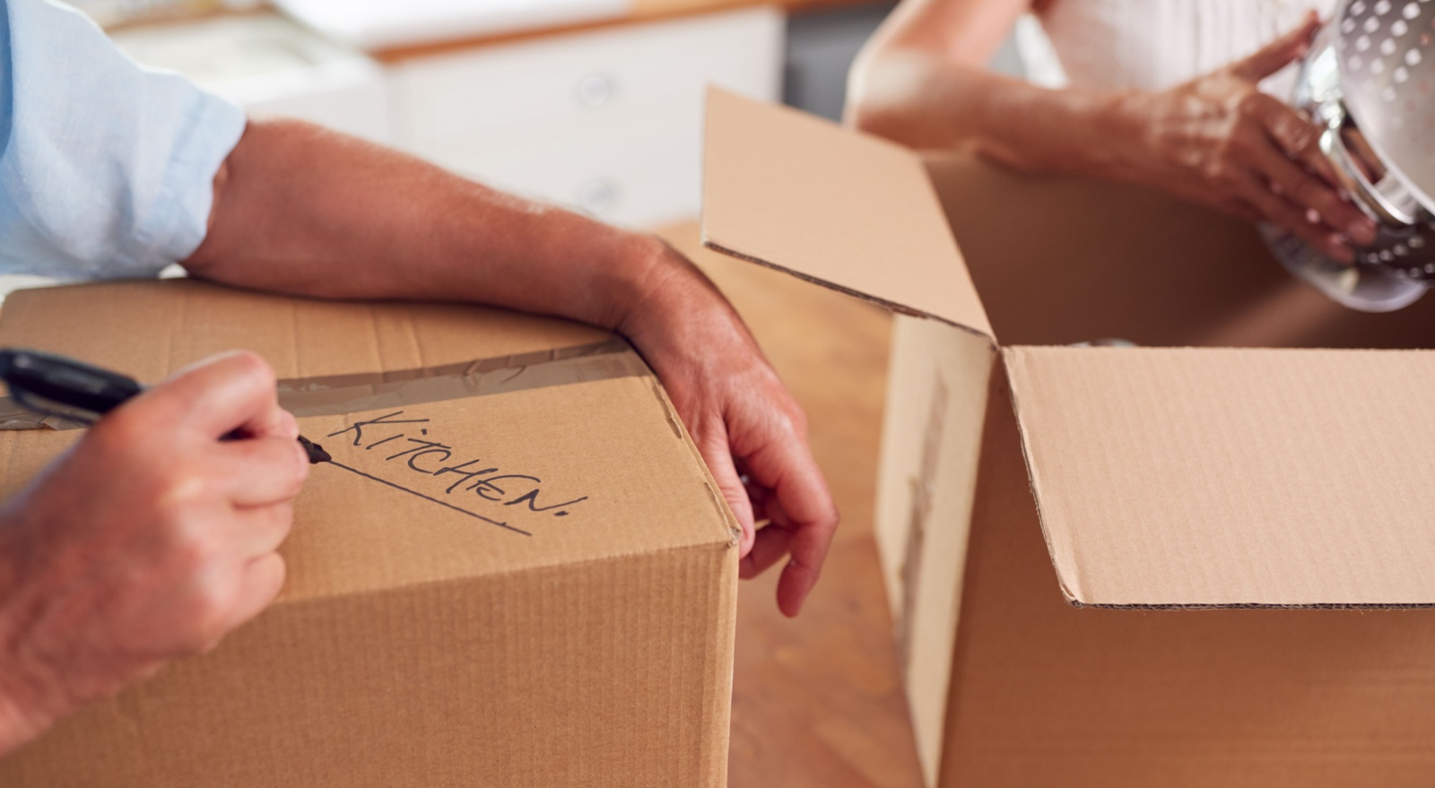 A close-up of a couple packing boxes to move home.