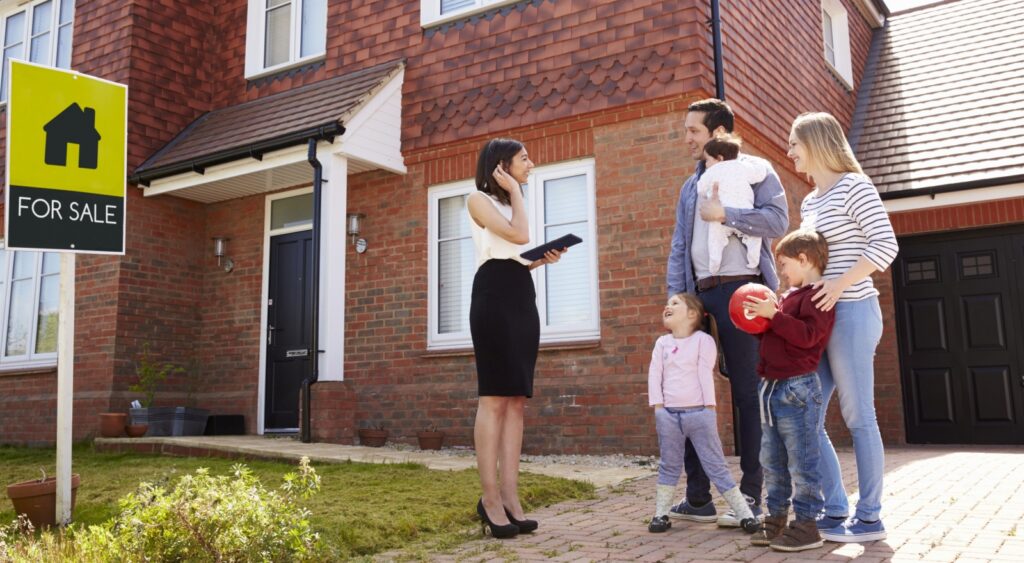 A family standing outside a house with a real estate agent.
