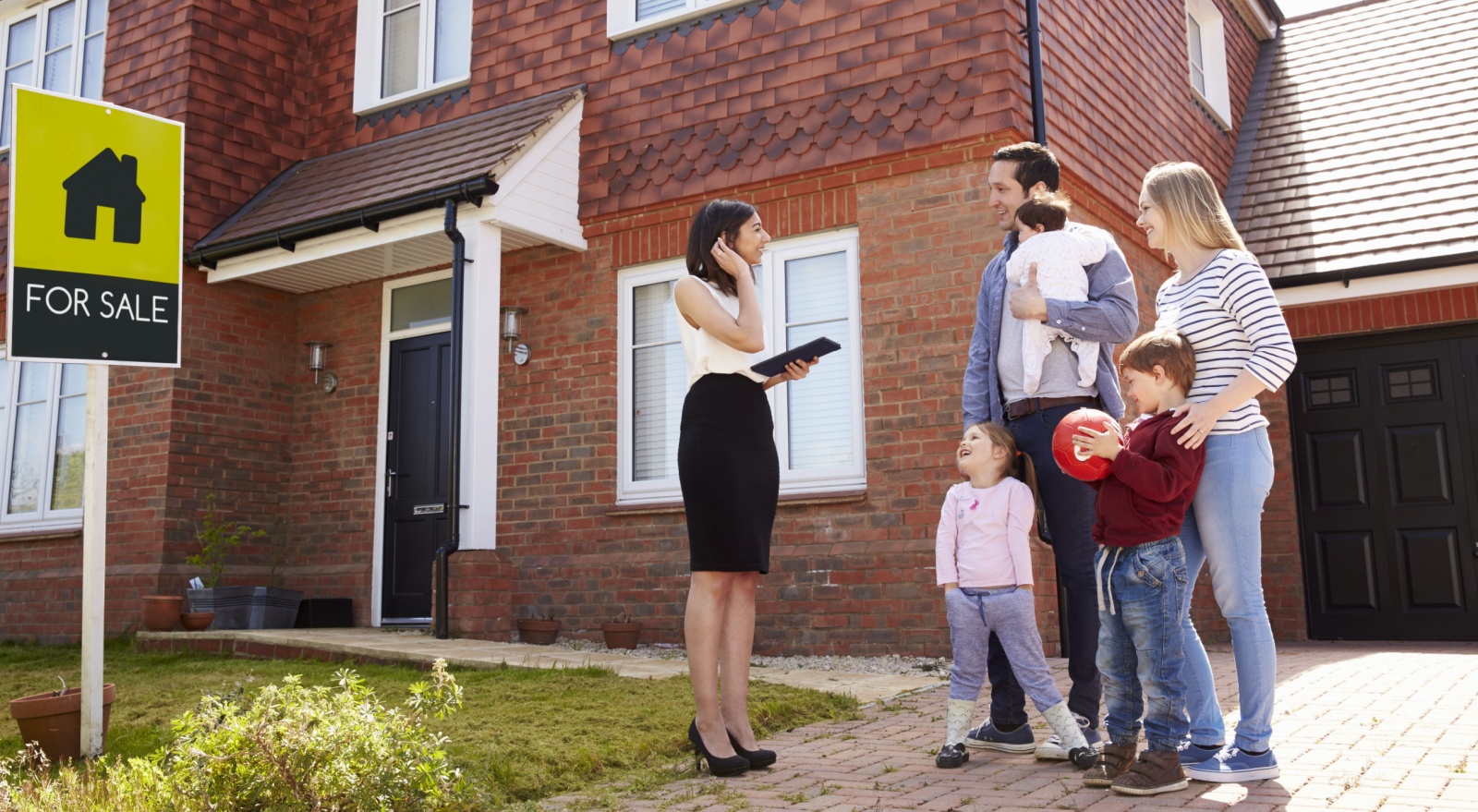 A family standing outside a house with a real estate agent.