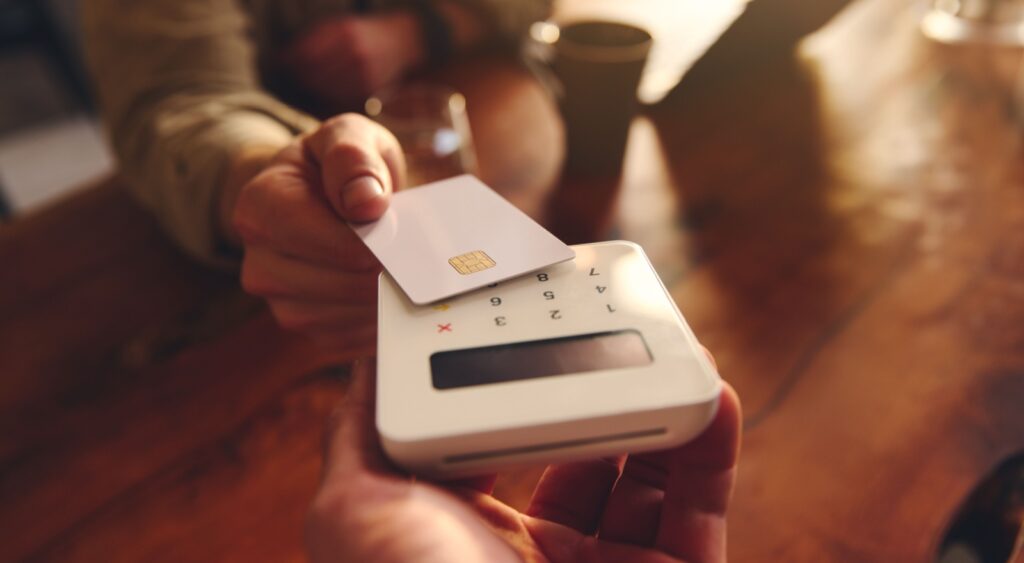A person using their debit card to pay in a café.