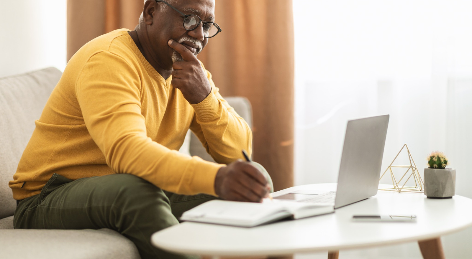 A man writing notes at a coffee table.