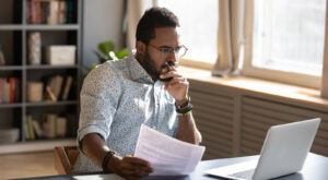 A man looking contemplatively at a desk.