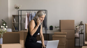 Female boss taking notes on a laptop as she discusses with someone on the phone