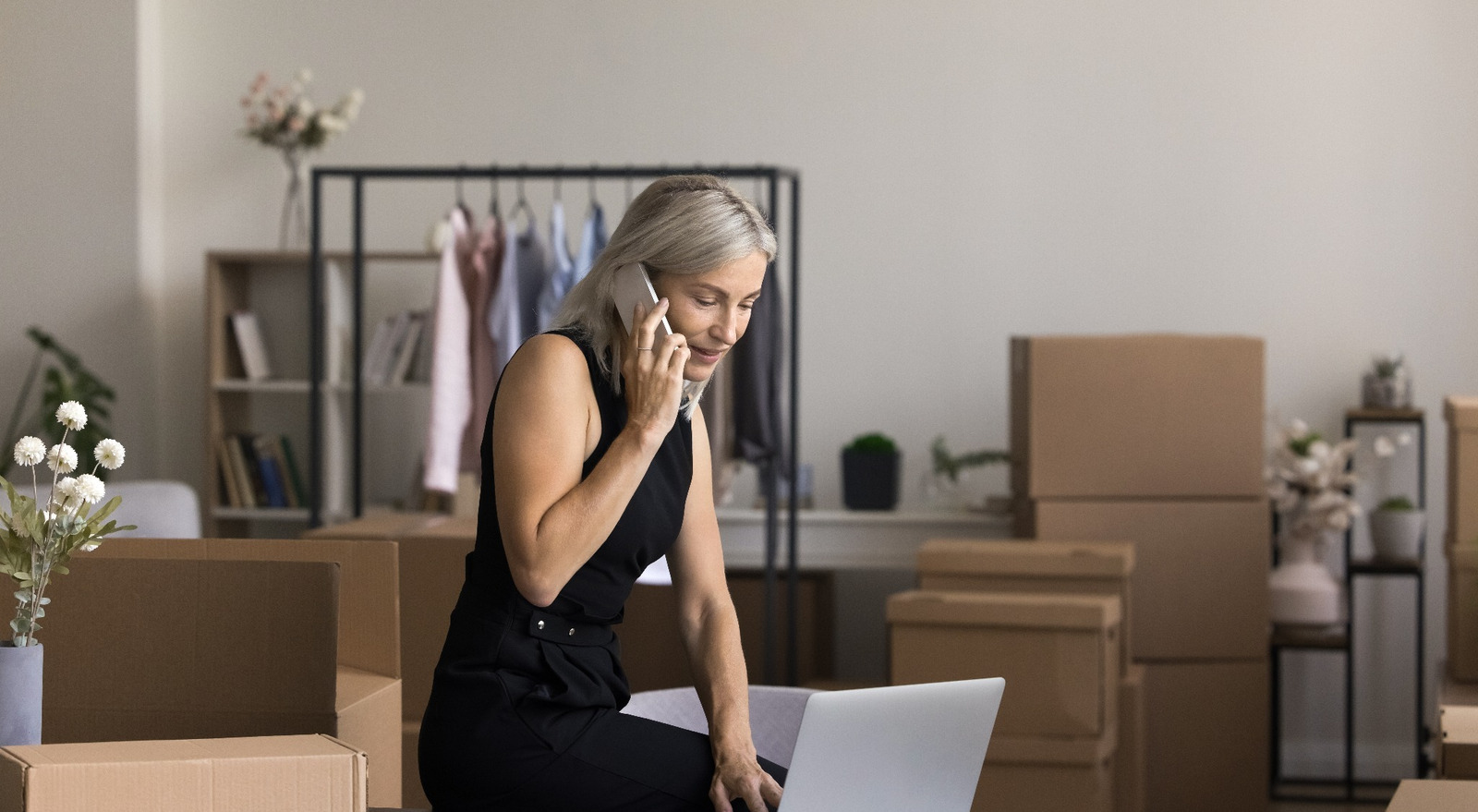 Female boss taking notes on a laptop as she discusses with someone on the phone