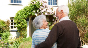 Rear view of senior couple outside pretty cottage