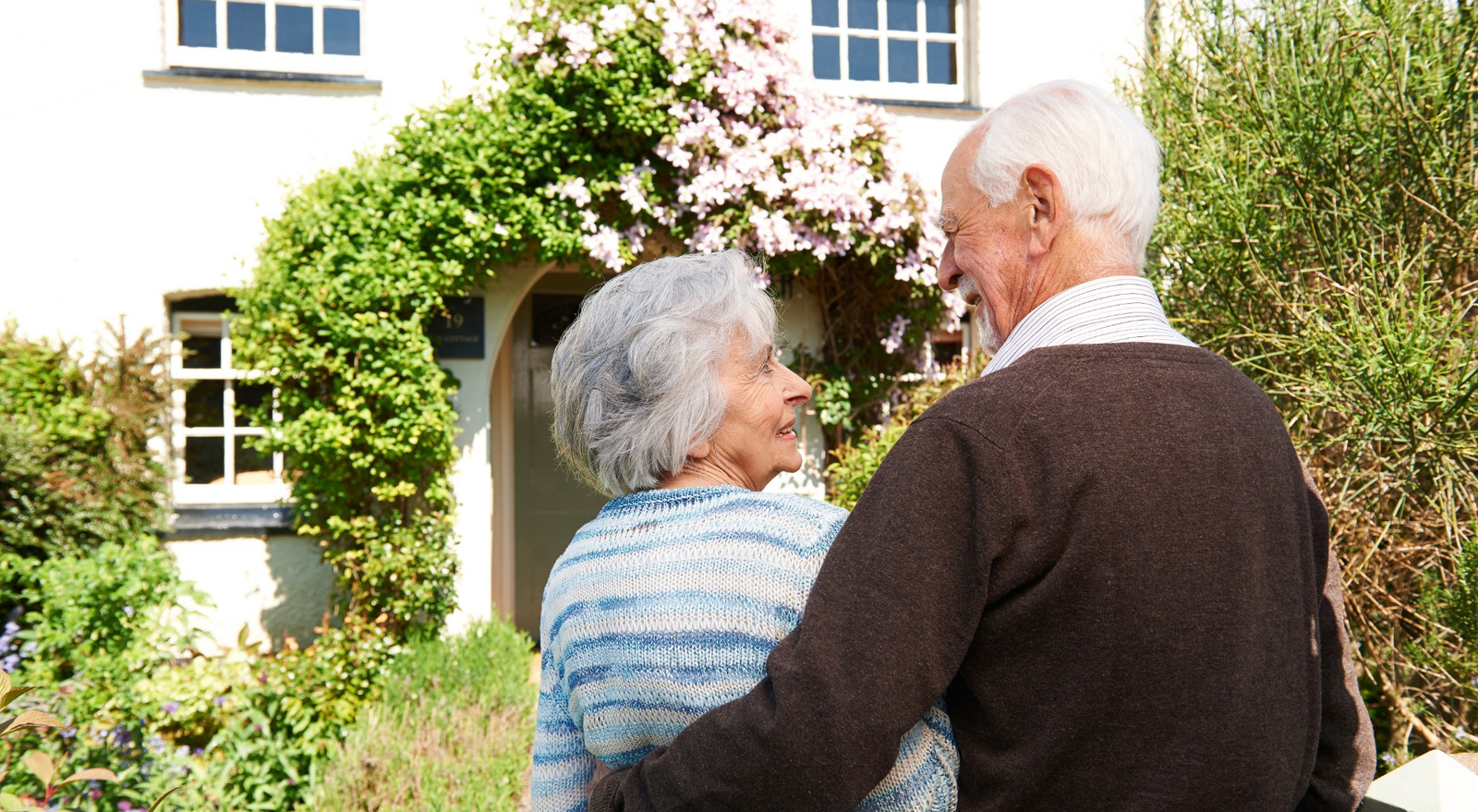 Rear view of senior couple outside pretty cottage